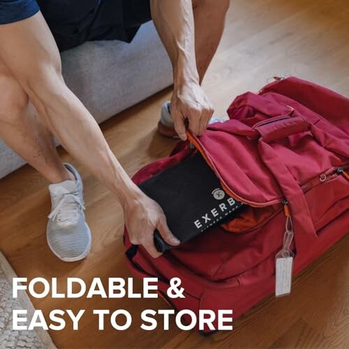 Person storing a foldable exercise mat in a red bag.